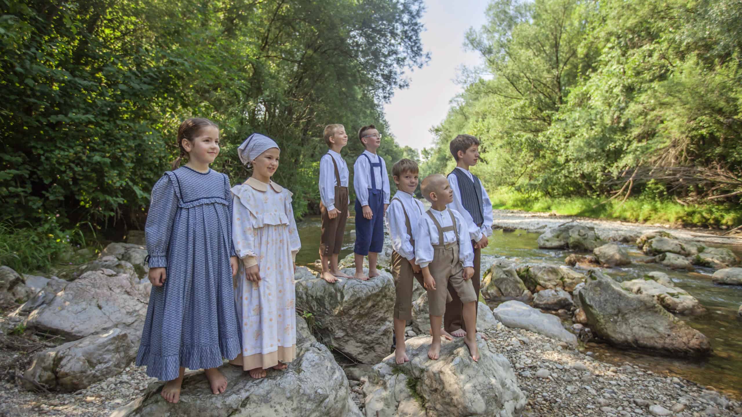 DOMZALE, SLOVENIA - Jun 30, 2019: Children in poor, old clothes play at river on sunny morning