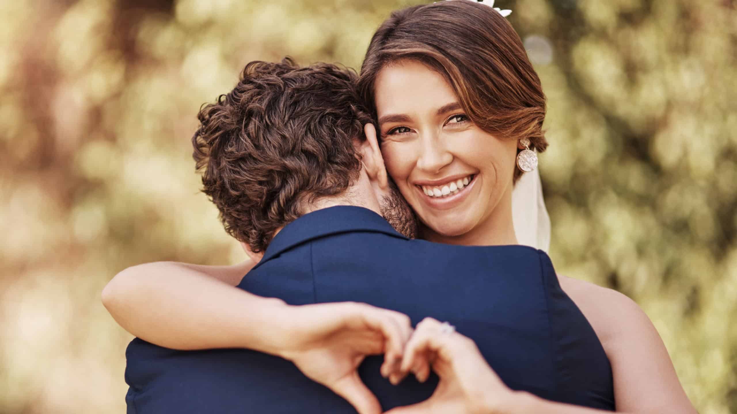 I love him too much. Cropped shot of an affectionate young bride smiling while making a heart shape on her grooms back on their wedding day.