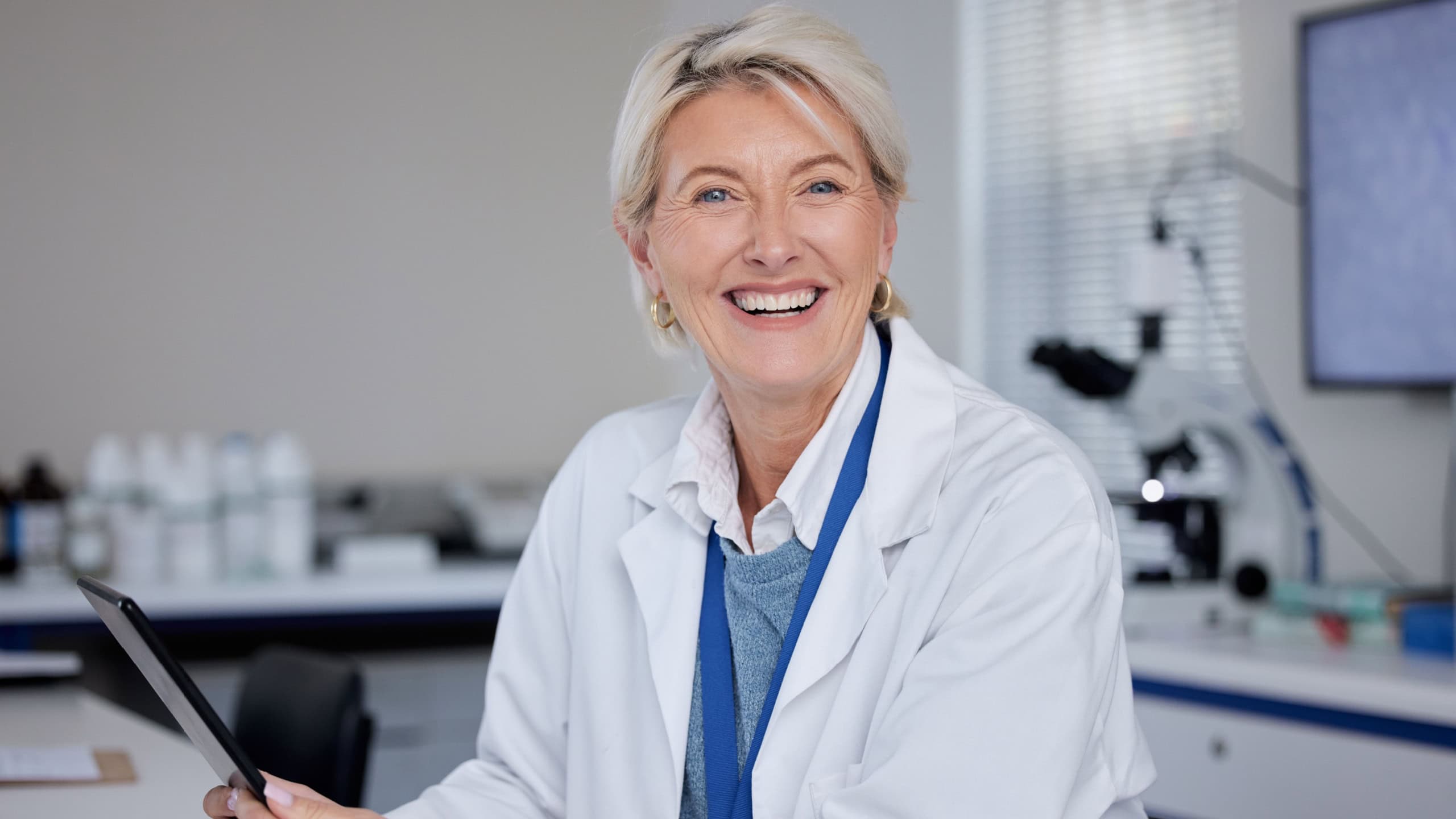 Portrait, doctor and senior woman with tablet in laboratory for science or medical research. Scientist, technology and smile of happy elderly female researcher from Canada holding digital touchscreen