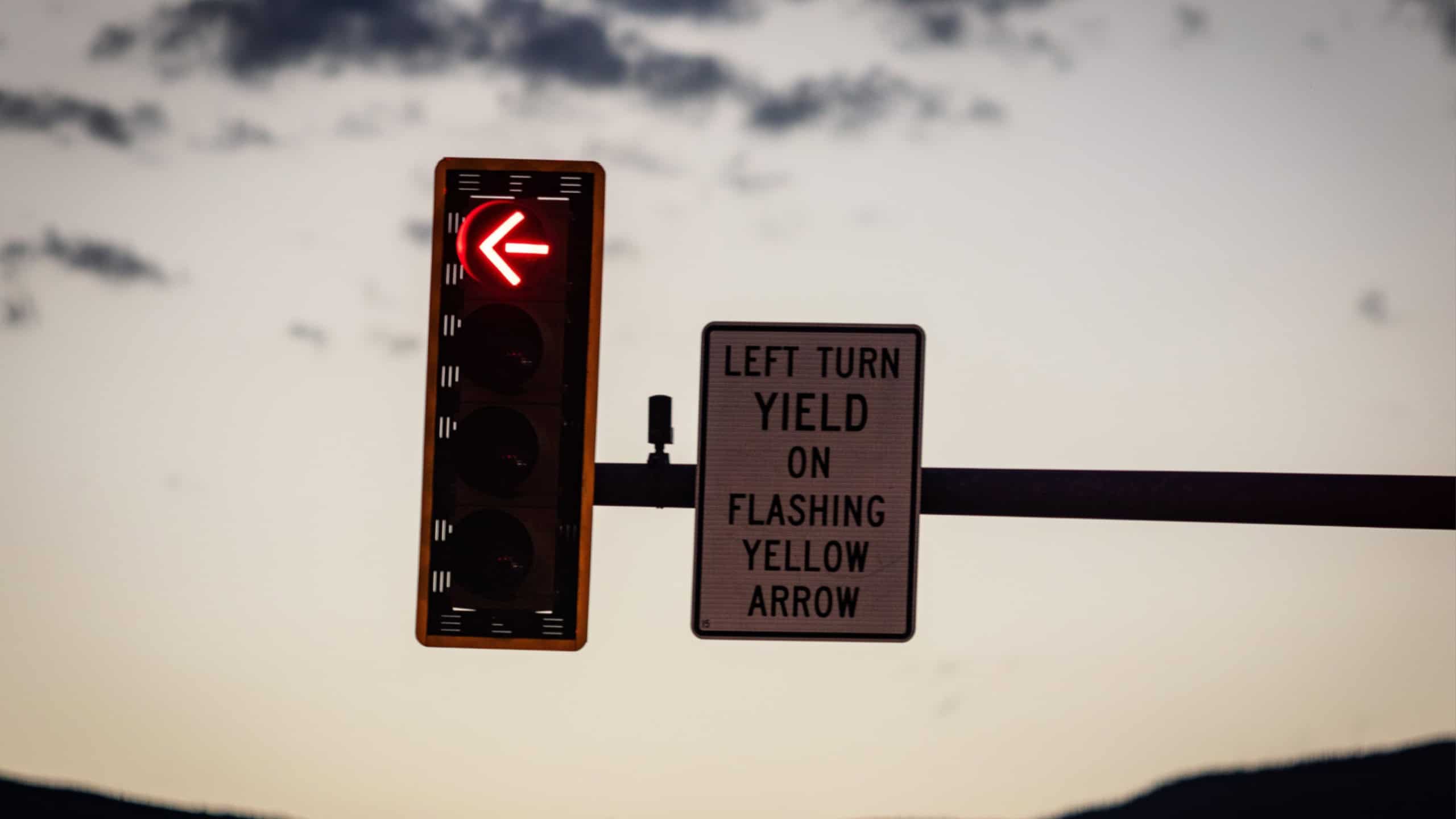 A closeup shot of a traffic light and sign indicating "left turn yield on flashing yellow arrow"