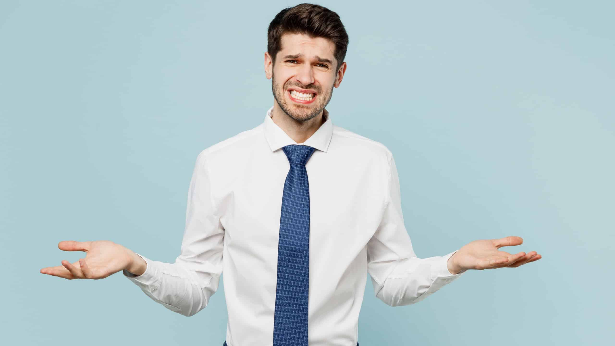 Young employee business man corporate lawyer wear classic formal shirt tie work in office shrugging shoulders look puzzled spread hands isolated on plain pastel light blue background studio portrait