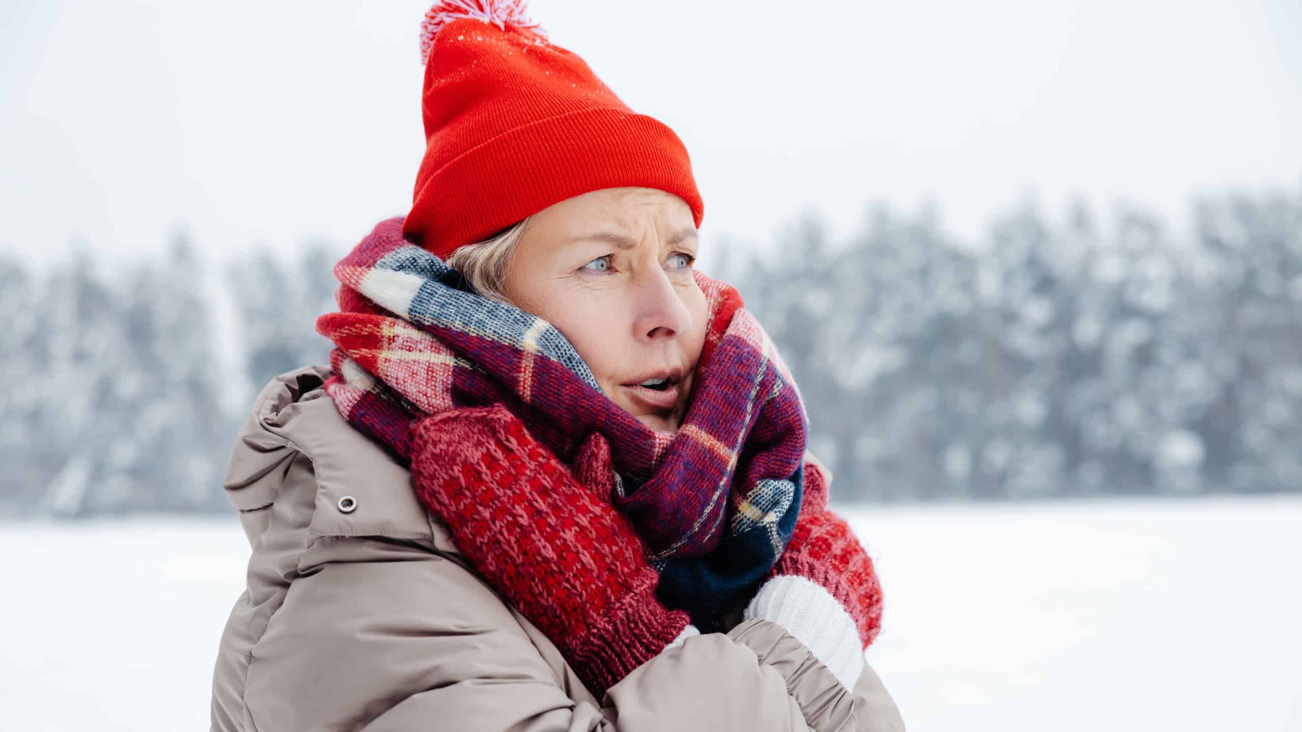 Woman red hat and checkered scarf feeling cold and shivering