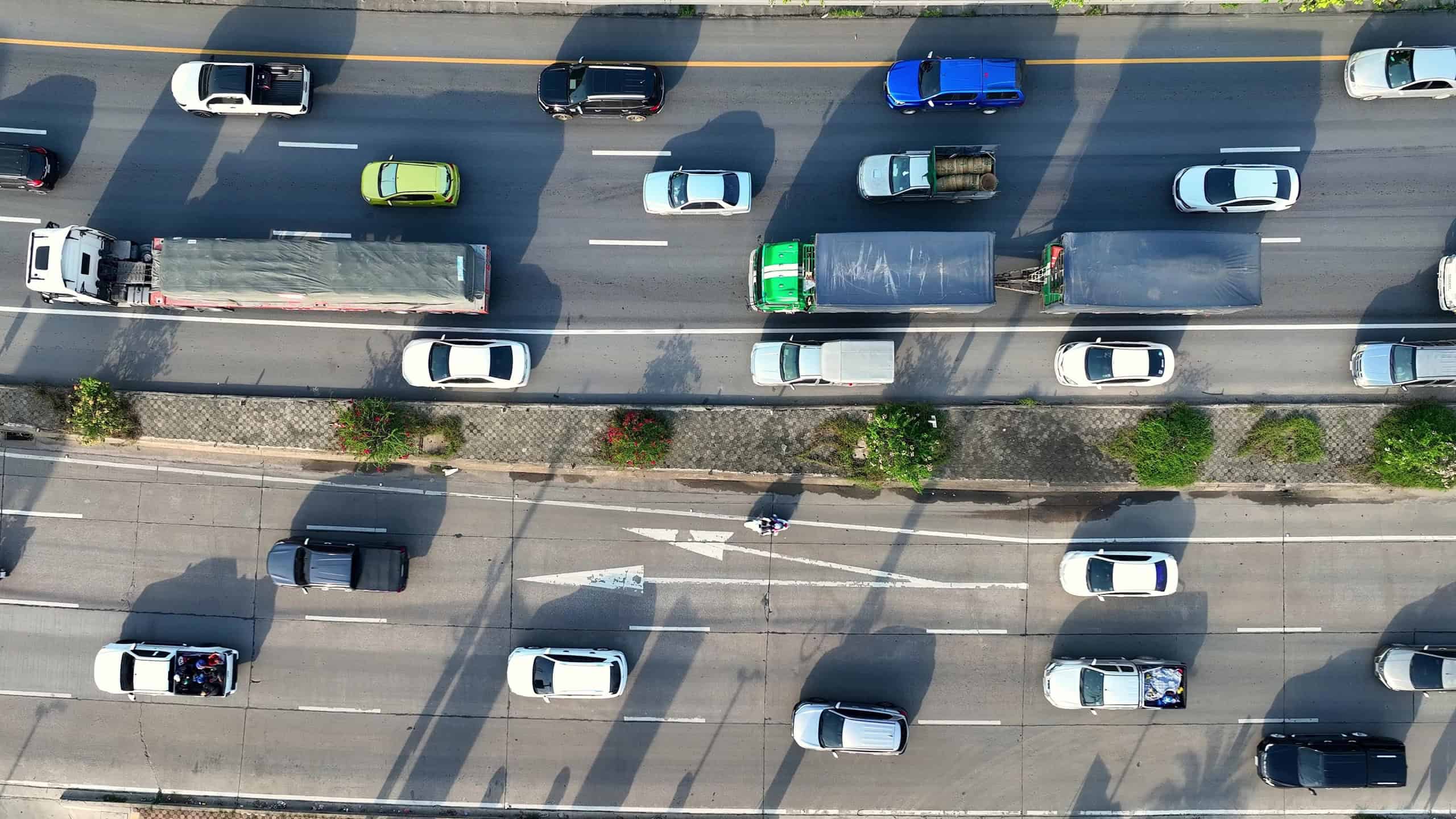 The motorway, snarled in a frustrating traffic jam, as seen from a drone's aerial perspective. A sea of stalled vehicles stretches endlessly in both directions, painting a picture of urban congestion.