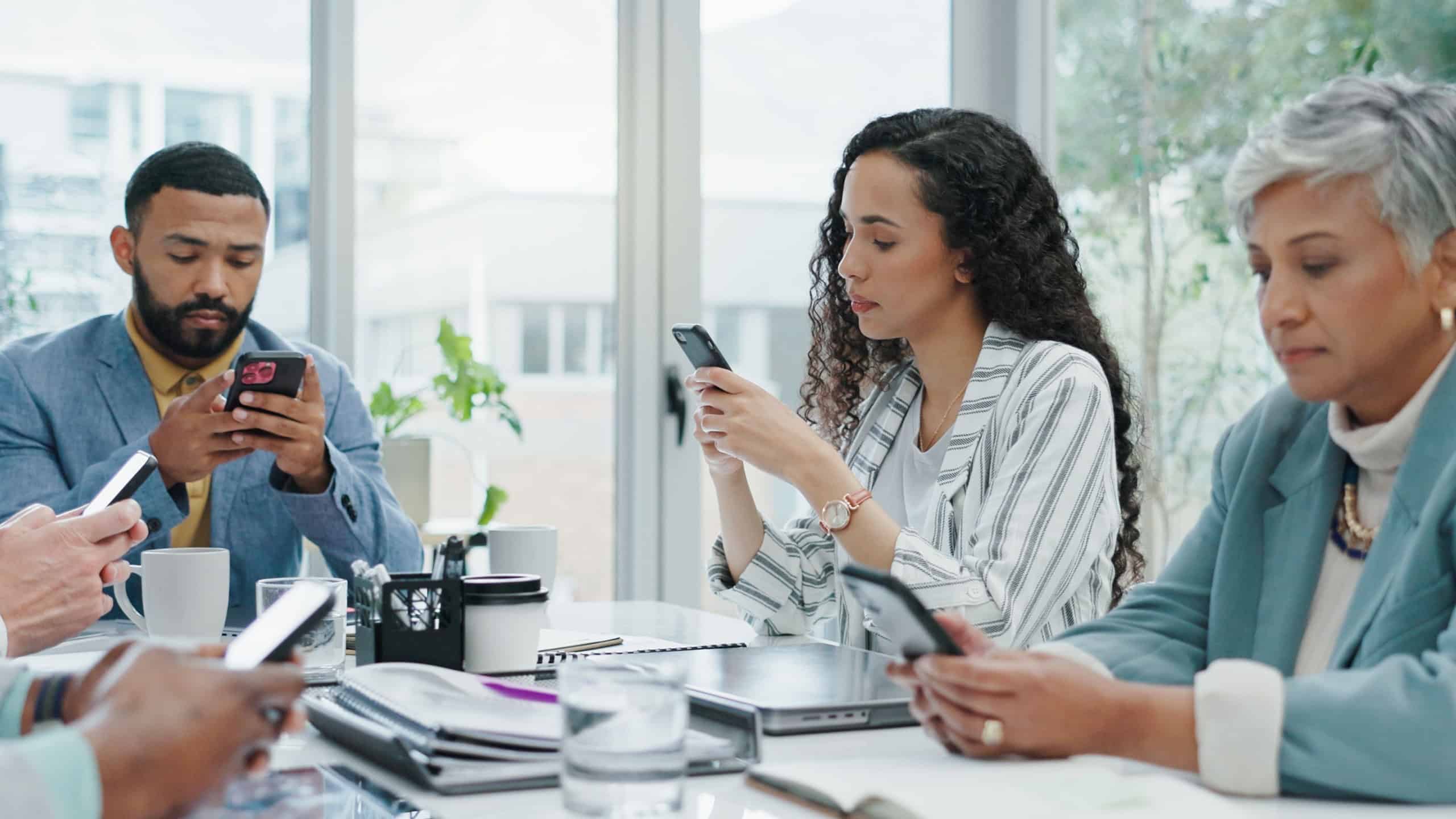 Phone, typing and distracted business people in office checking email, social media or online chat. Communication, connectivity and careless team in conference room with smartphone, addiction or risk