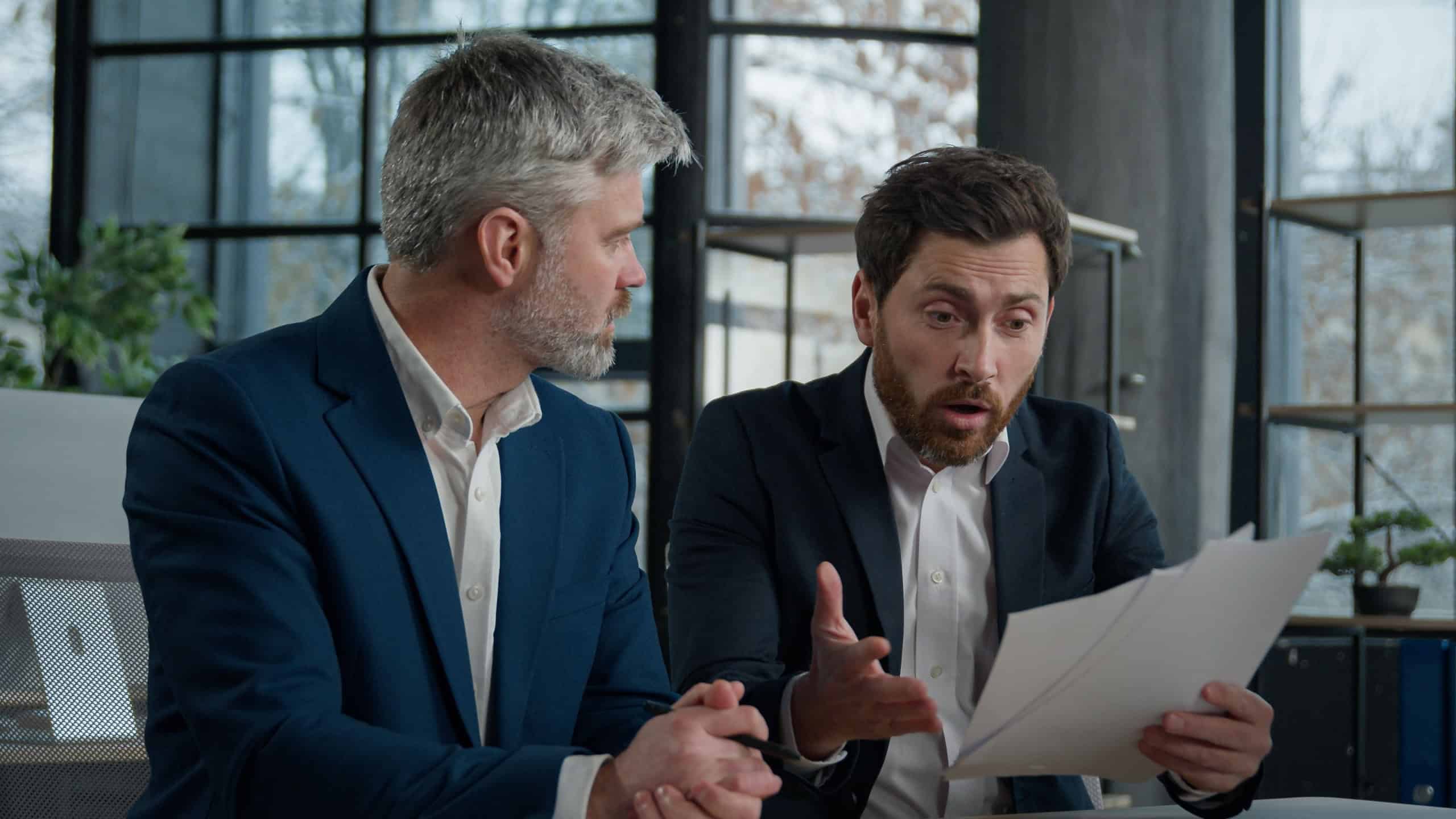 Nervous angry man boss argue scolds employee because mistake in documents financial papers Caucasian men businessmen arguing in office meeting business conflict problem mistake work failure bad result