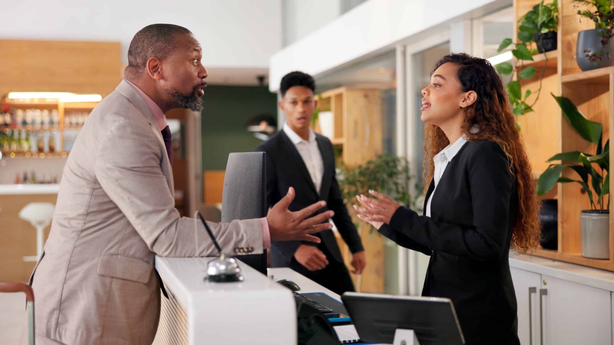 Businessman, woman and angry at cafe with stress, argument and complaint for bad service at hotel. People, dispute and frustrated with conflict, fight and talking by counter with question for staff