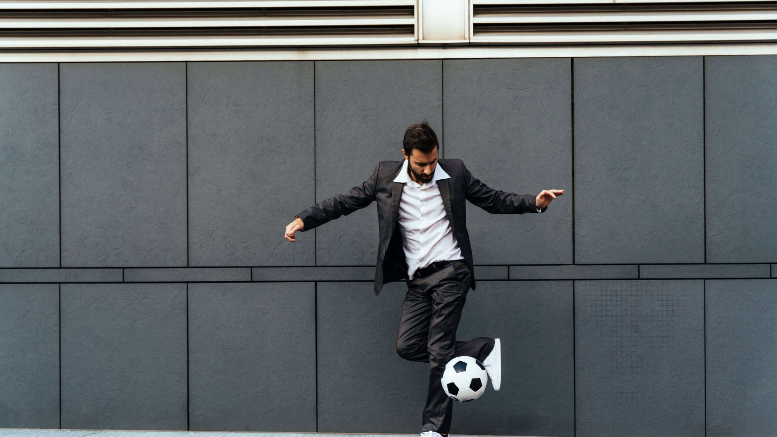 Image of a businessman and soccer freestyle player making tricks with the ball on the street. Concept about sport and business people