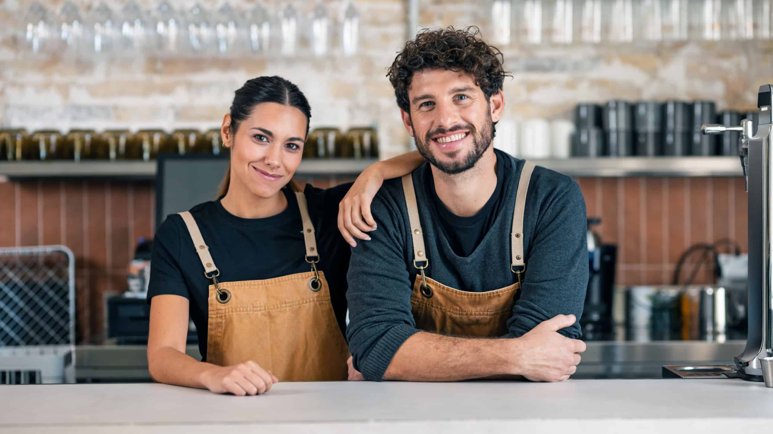 Portrait of two younger waiters looking at camera in a pastry shop.