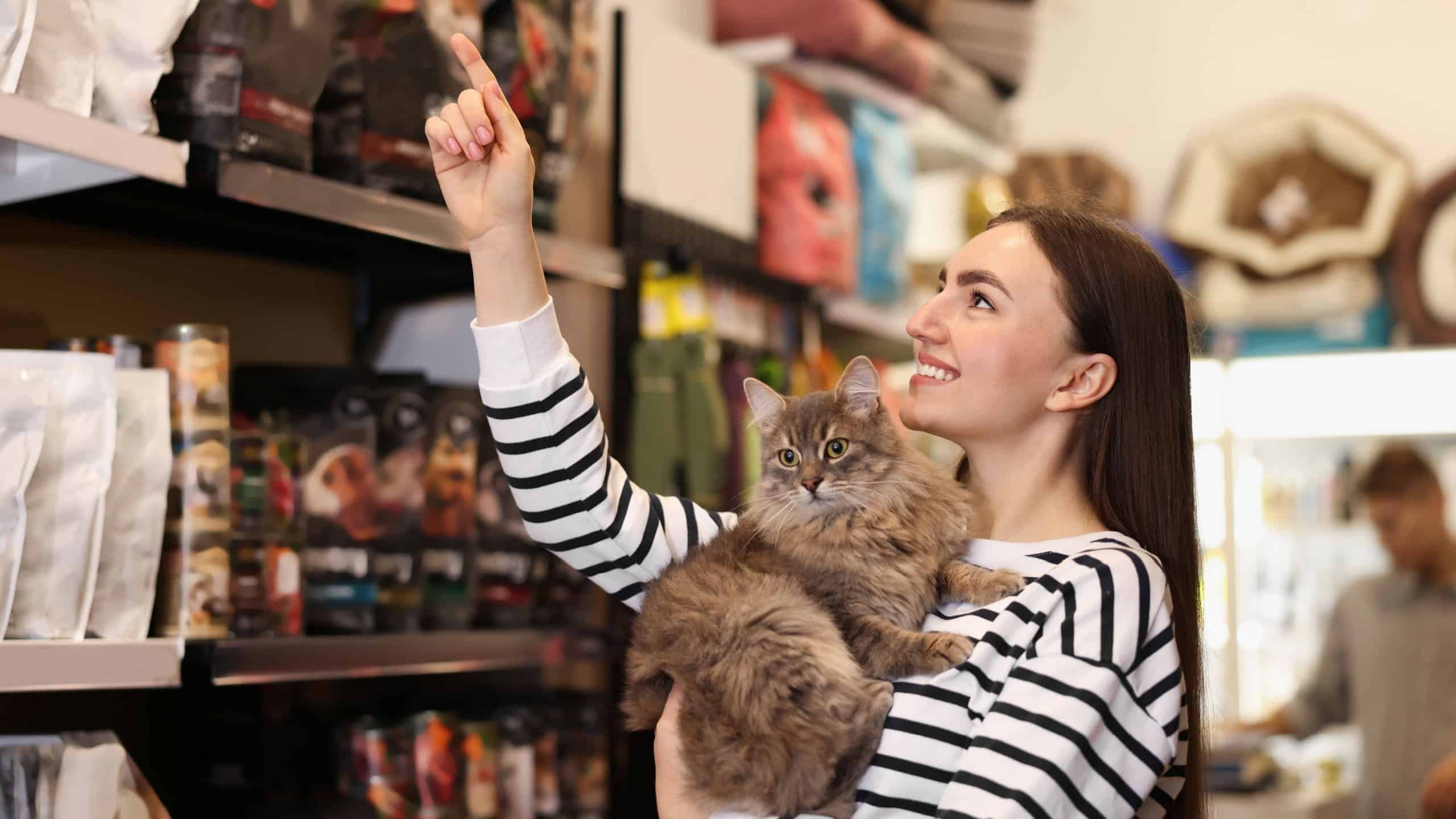 Woman with her cute cat in pet shop