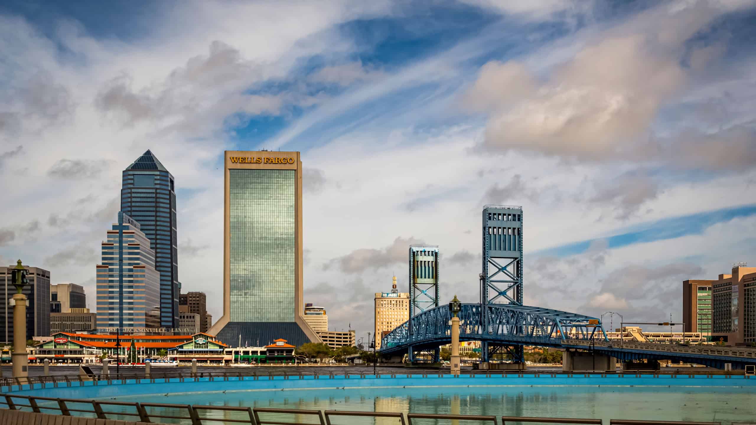 Jacksonville, FL, USA - December 14, 2015: Urban skyline of Jacksonville, Florida and The Jacksonville Landing at the St Johns River and the John T Alsop Jr bridge under a partly cloudy sky.