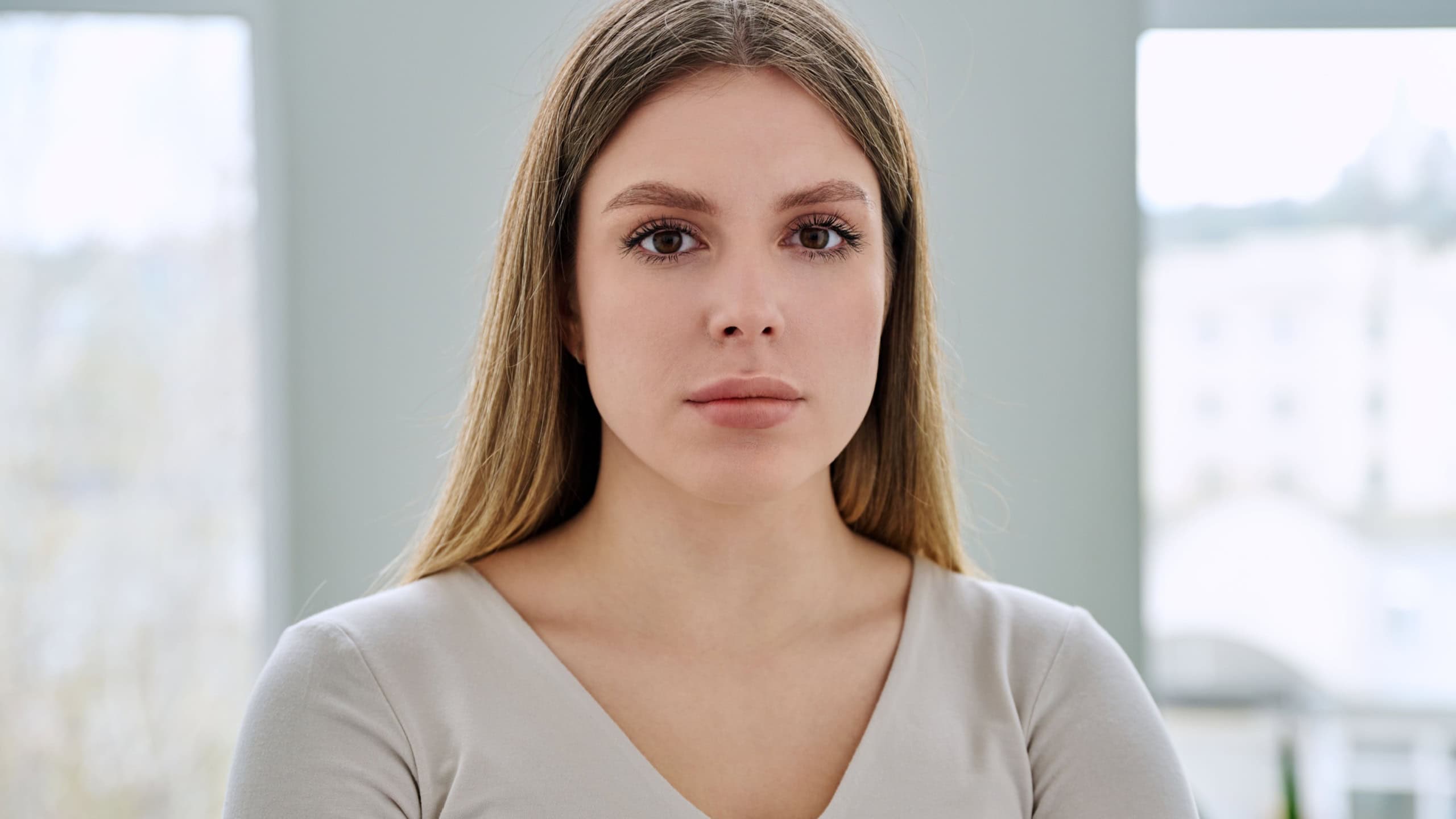 Headshot portrait of young serious woman posing in home