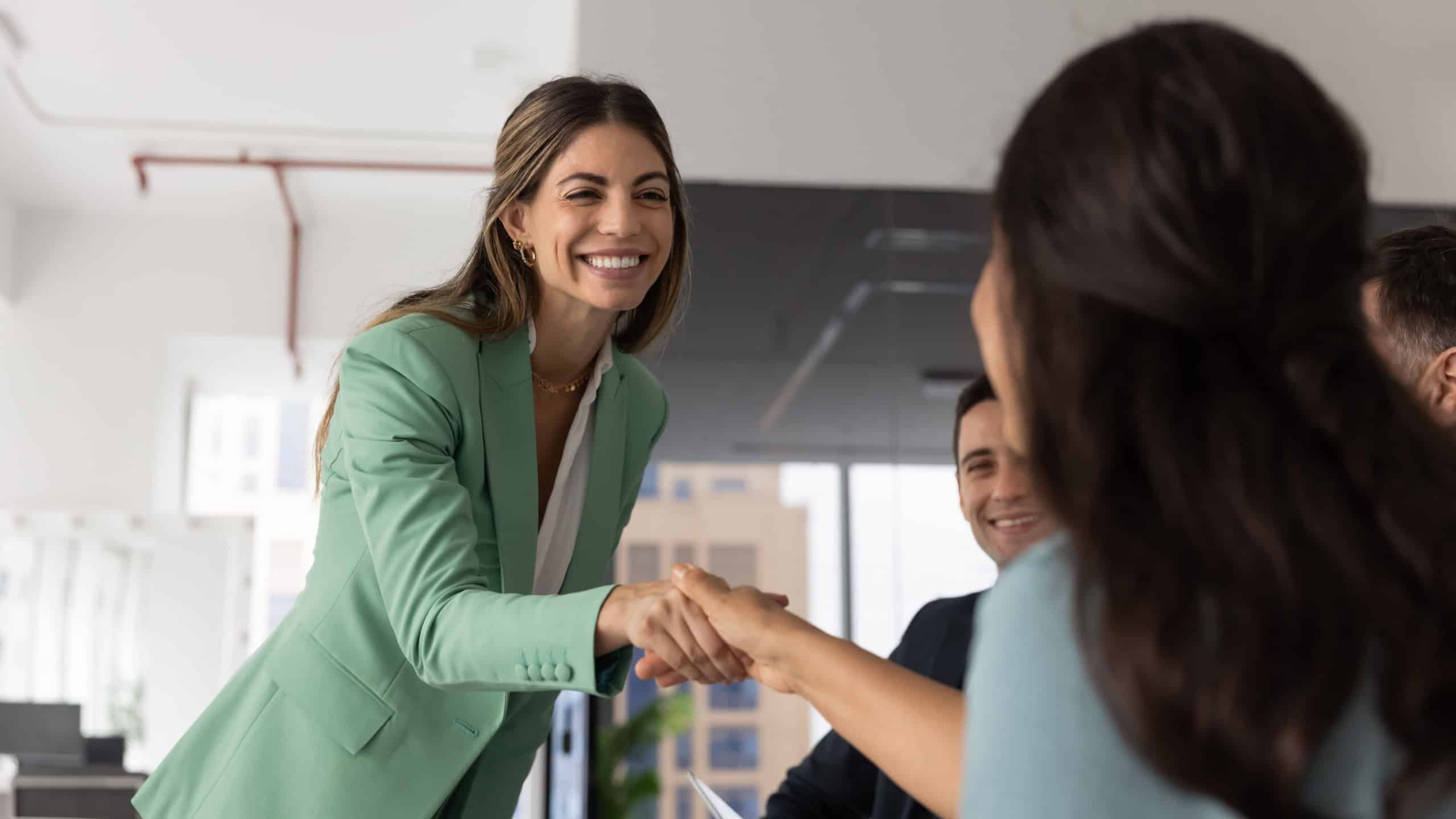 Happy businesswoman greeting colleague, finalize business meeting or briefing event in contemporary office. Business etiquette, gesture of making deal, start partnership and thanking for collaboration
