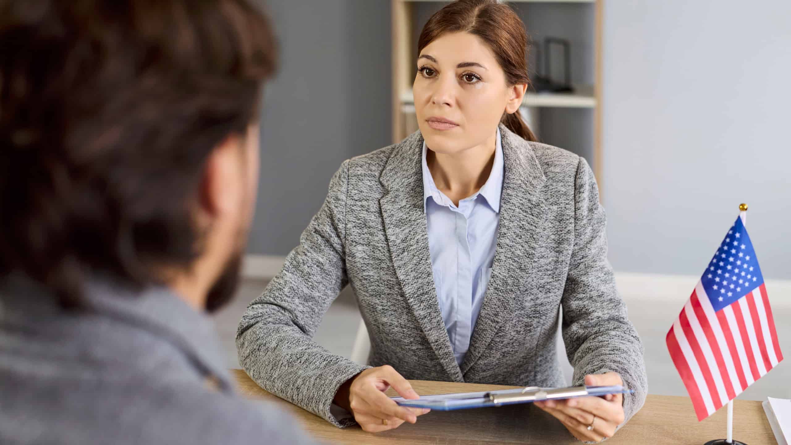 Consular visa interview with USA officer reviewing documents in public services or embassy. Immigration applicant answers questions and presents forms during a citizenship review seeking approval.