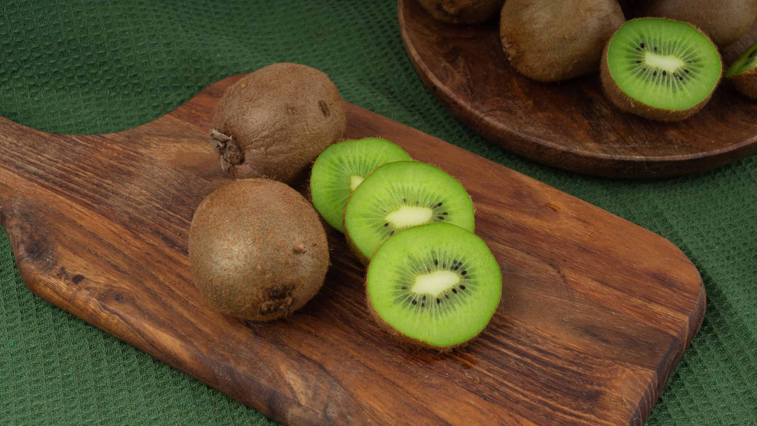 Kiwi fruits on wood cutting board. Green sliced kiwifruit, furry kivi cuts, fresh juicy tropical fruits with seeds, kiwi on rustic background