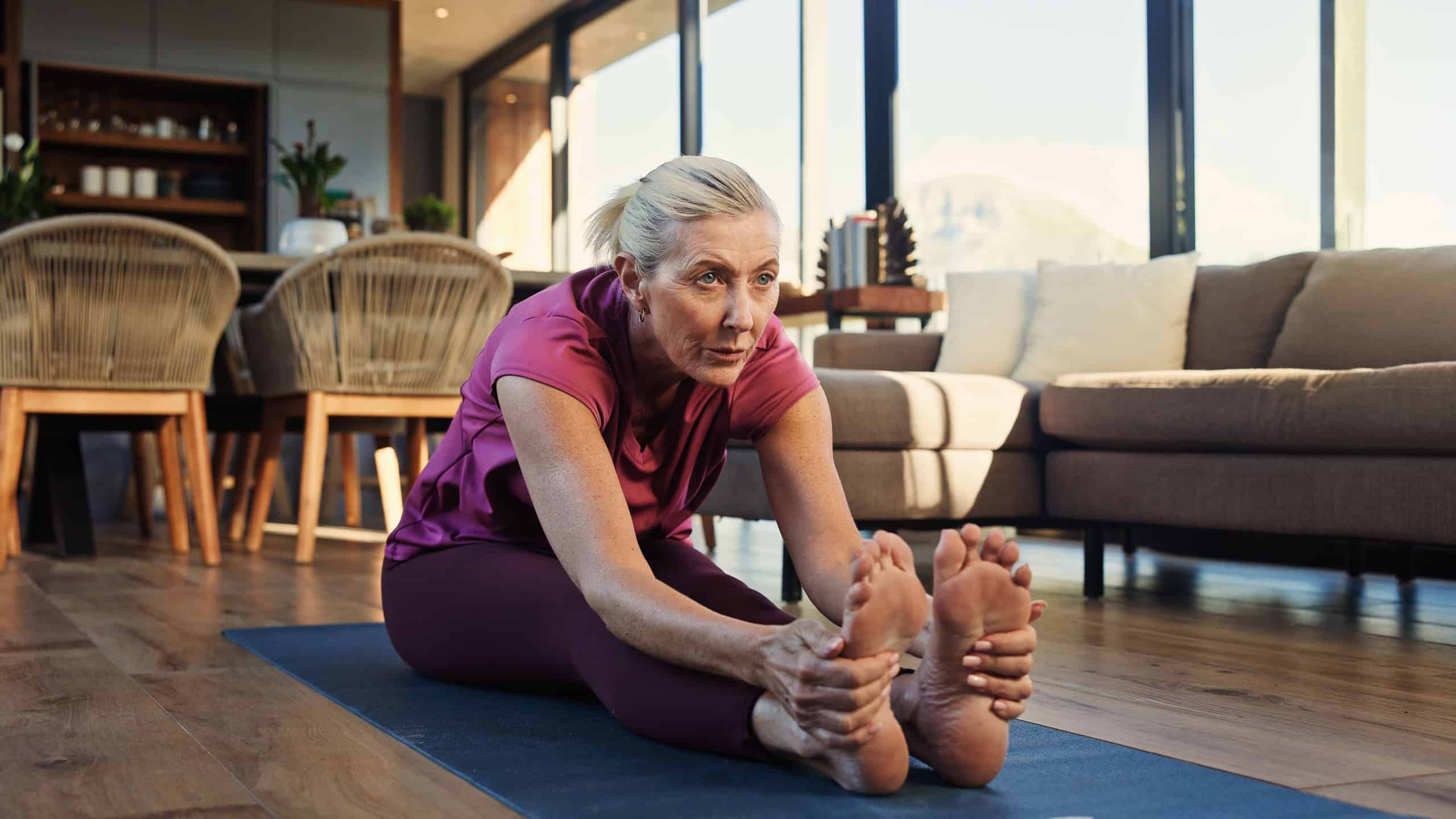 Yoga mat, stretching or senior woman in home for wellness, mobility practice or flexibility activity. Retirement fitness, morning routine or old person with forward bend exercise, pilates or health