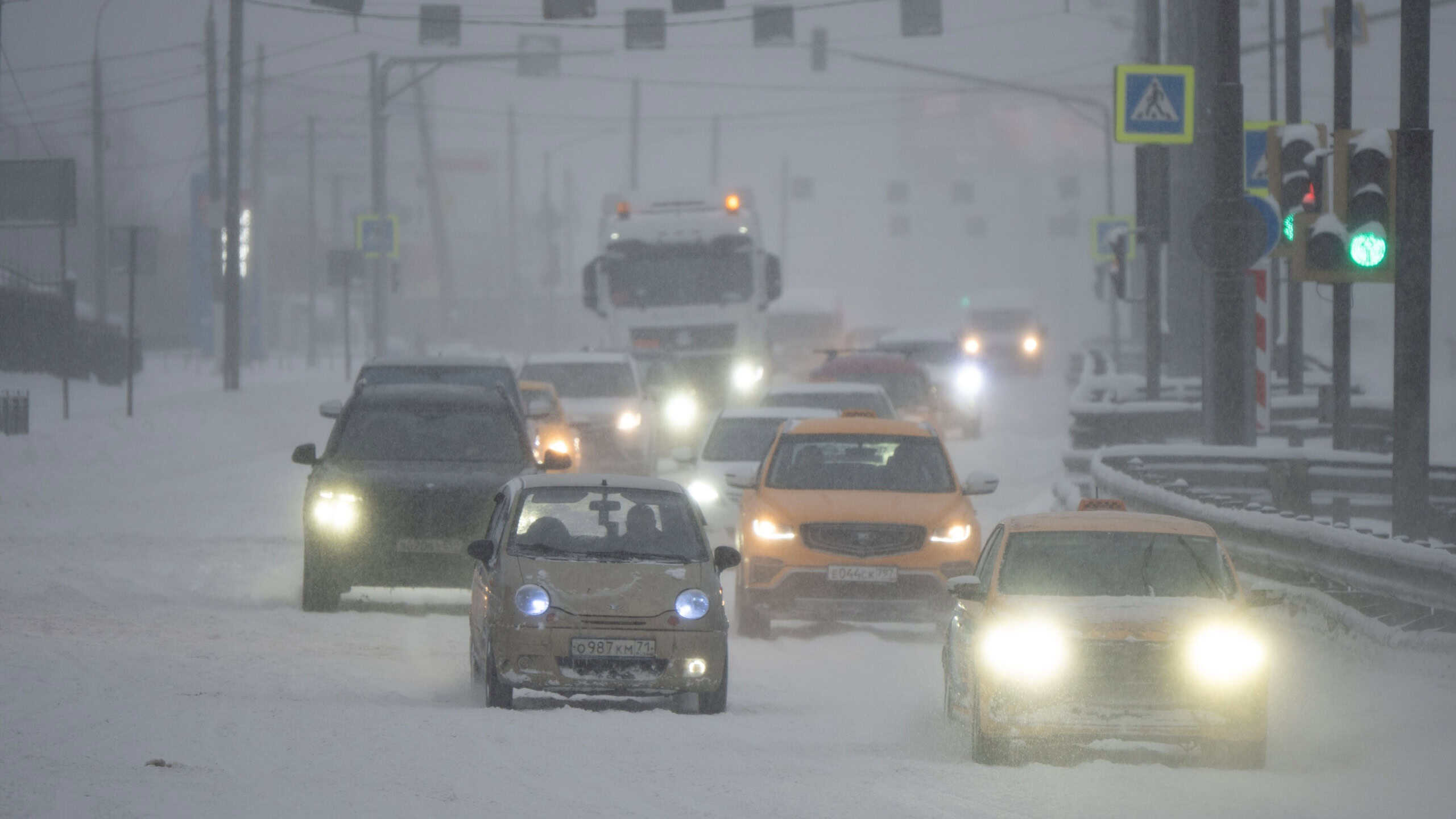 Moscow, Russia - 9 January 2026: Cars and truck commuting on a snow covered street during a severe winter blizzard, creating difficult driving conditions