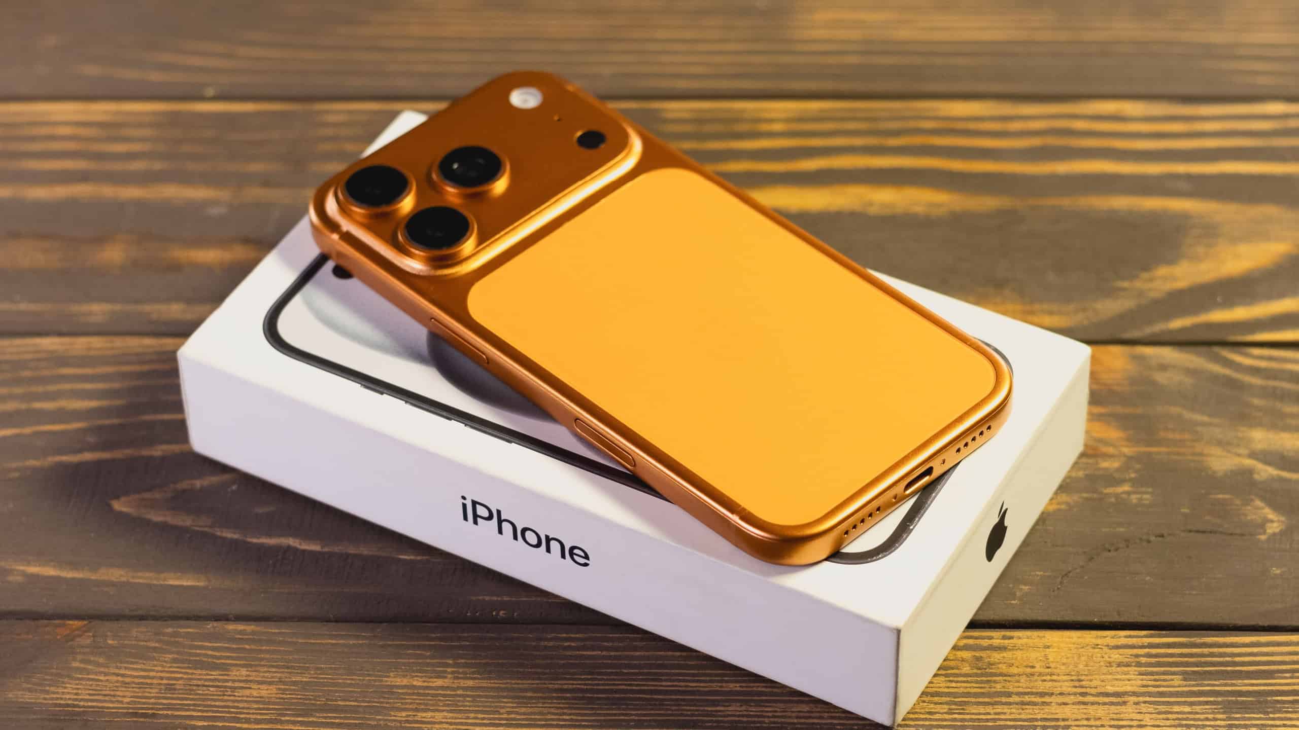 KYIV, UKRAINE - January 22, 2026 : Apple iPhone 17 Pro in Cosmic Orange color lie on box on wooden background.