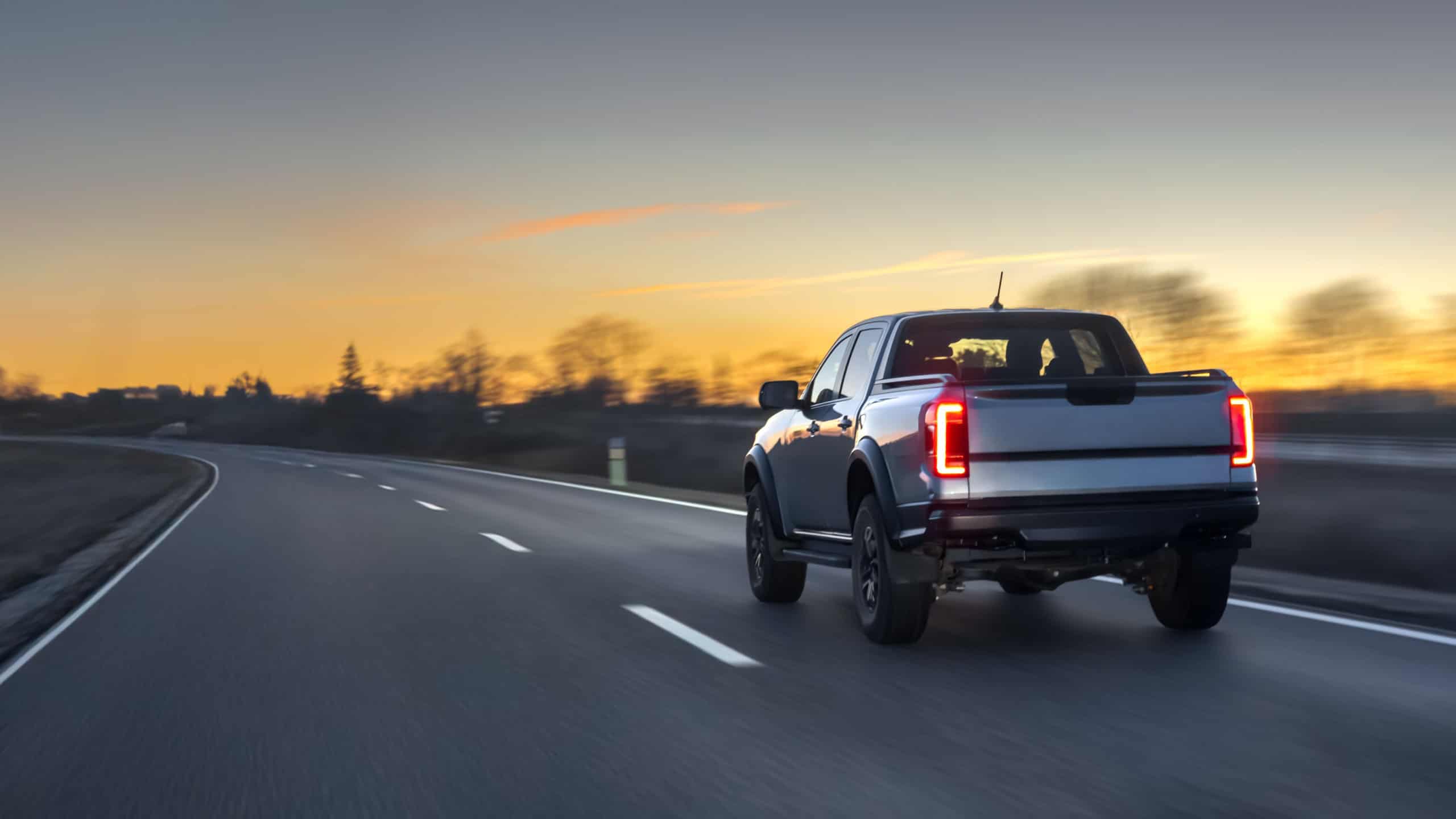 Pickup truck driving on open highway at sunset with motion blur. Pickup road travel.