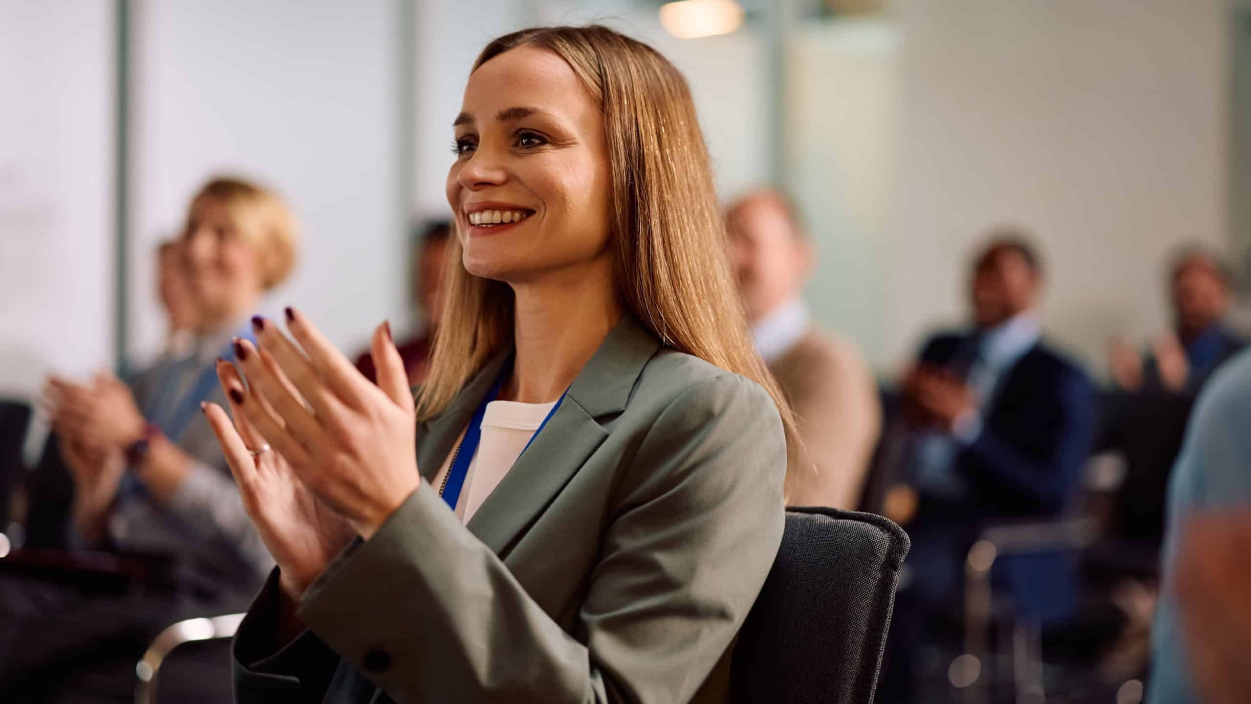 Happy businesswoman applauding after successful education event in board room.