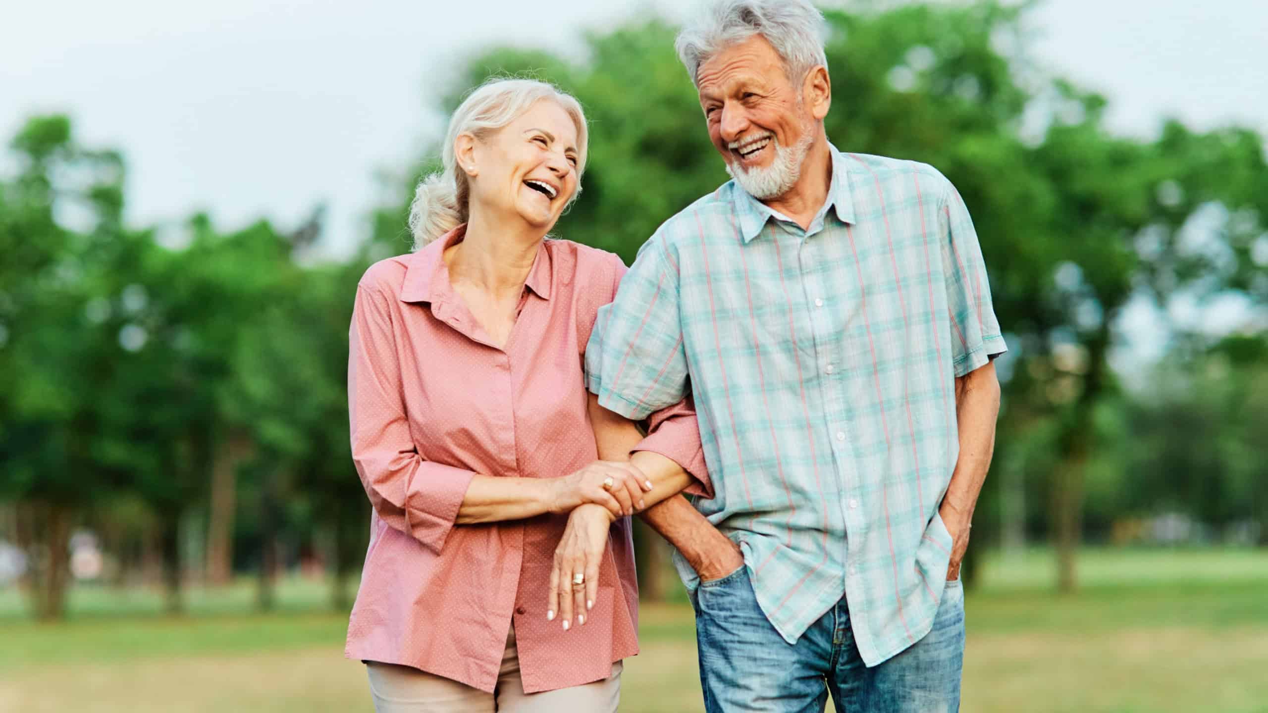 Happy active senior couple walking and holding hands outdoors