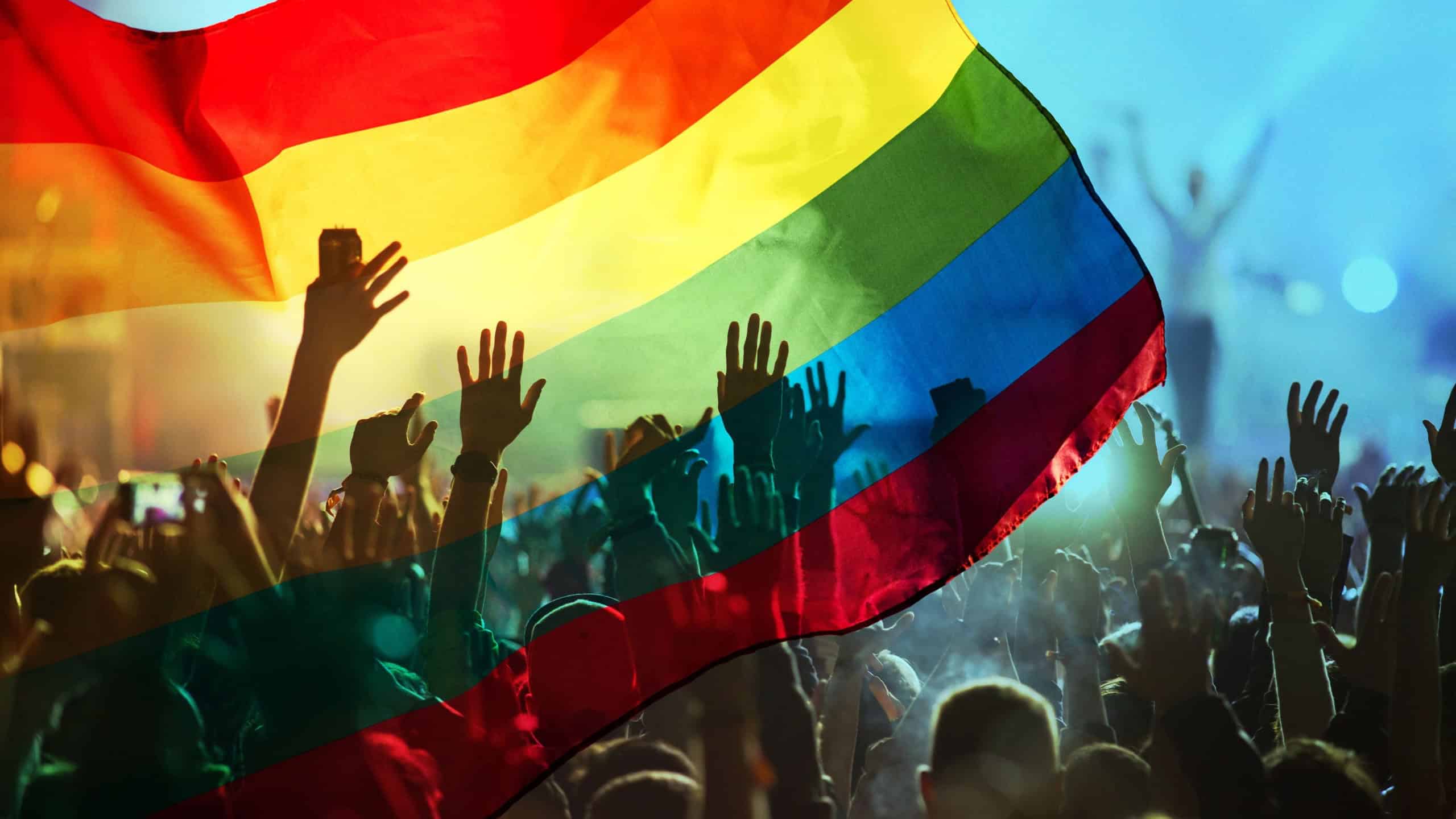 pride community at a parade with hands raised and the LGBT flag - symbol of love and tolerance