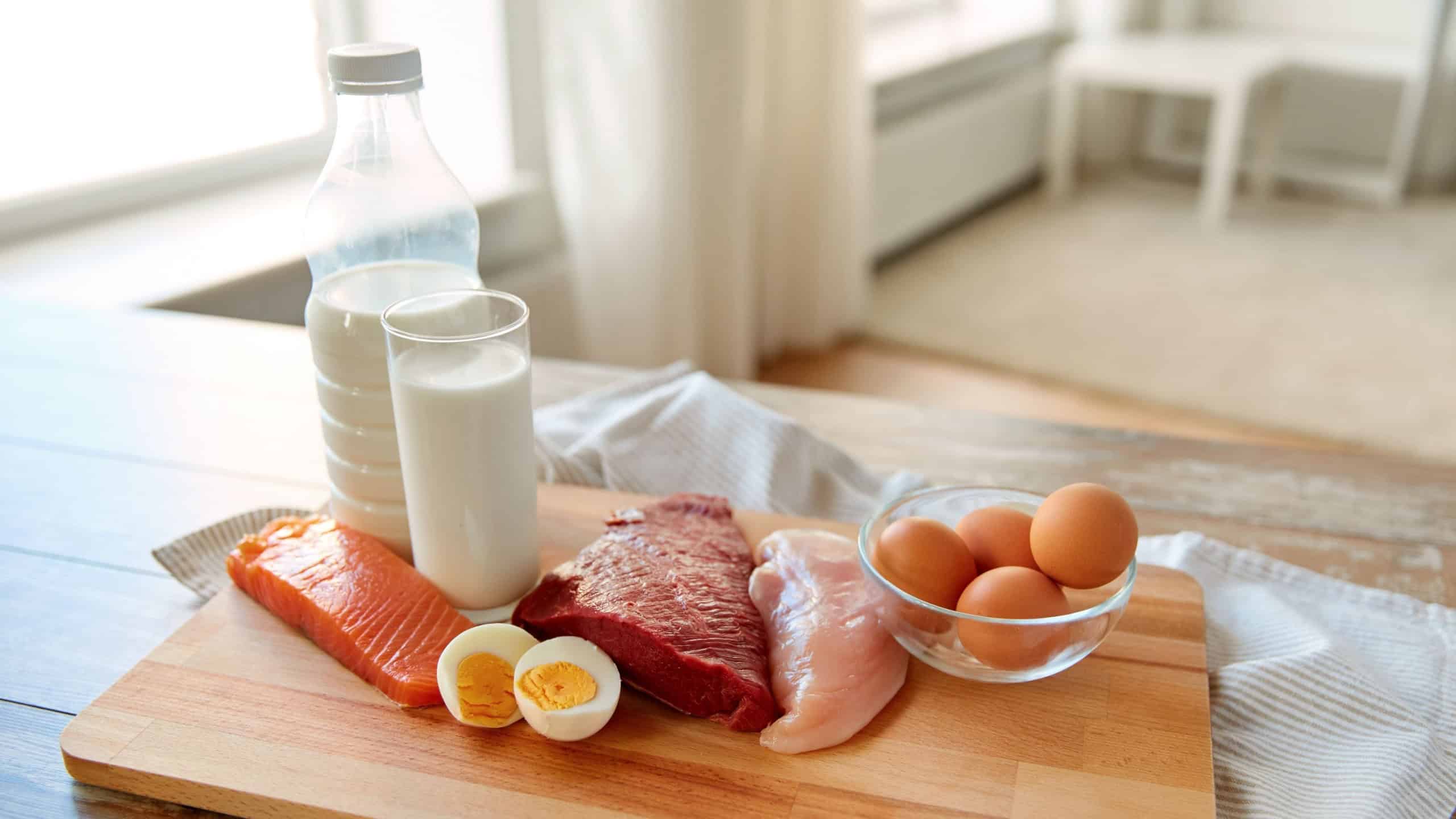 natural food, healthy eating and protein diet concept - raw meat fillet, fish, milk and eggs on wooden table