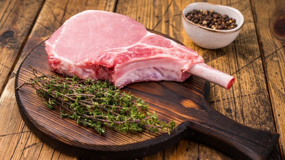 Pristine pork loin chop, featuring a thick cut and beautiful marbling, ideal for a hearty dinner. wooden background. top view.