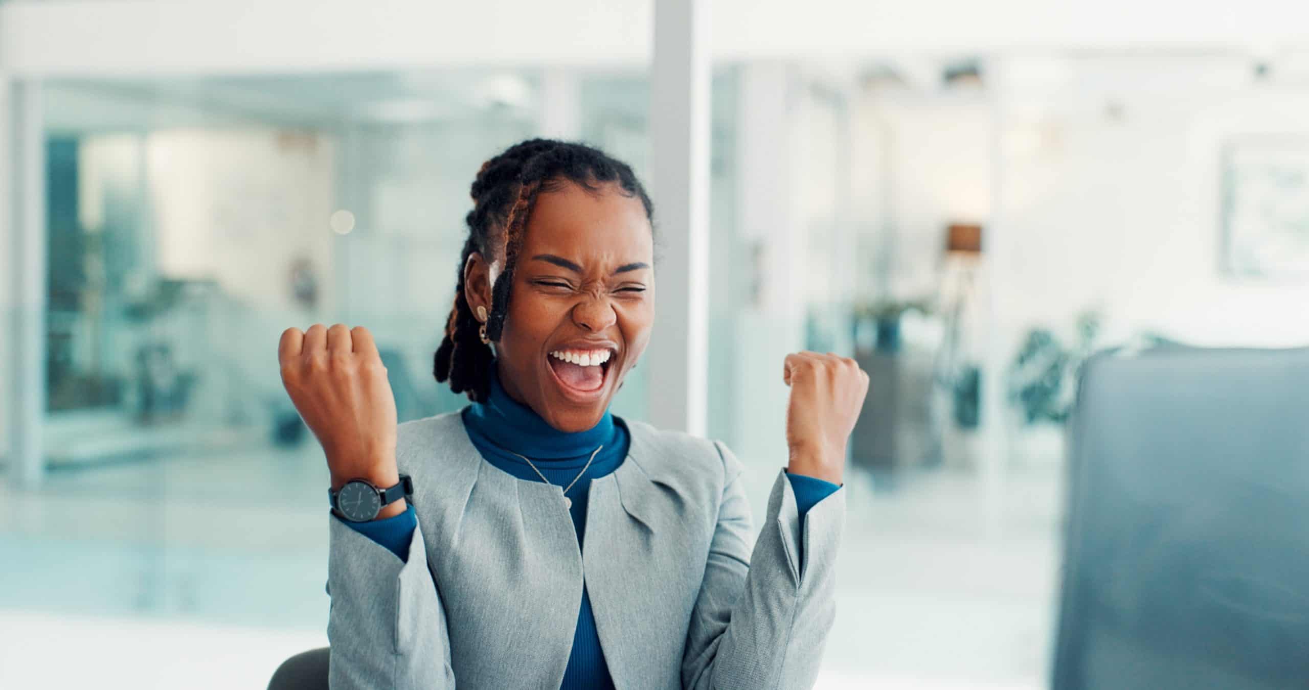 Business, woman and celebration with computer in office for article success, trending story and reward. Journalist, black person and tech with victory fist for blog recognition and career achievement