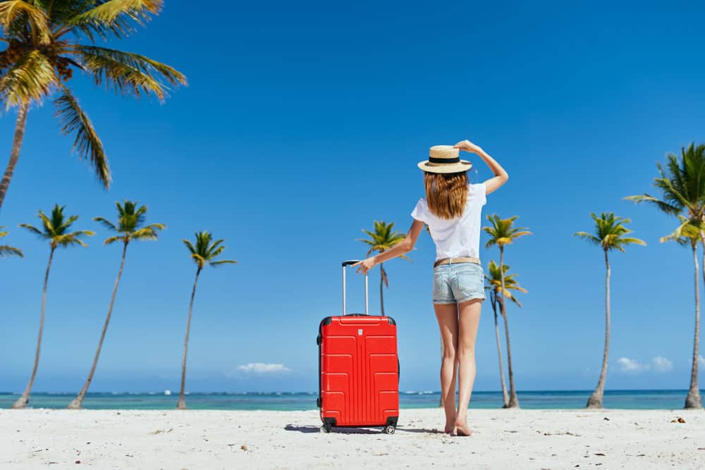 Suitcase on a tropical beach with palm trees