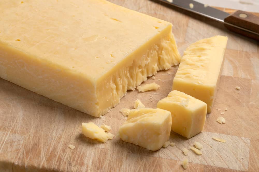 Extra mature english traditional cheddar cheese and pieces on a cutting board