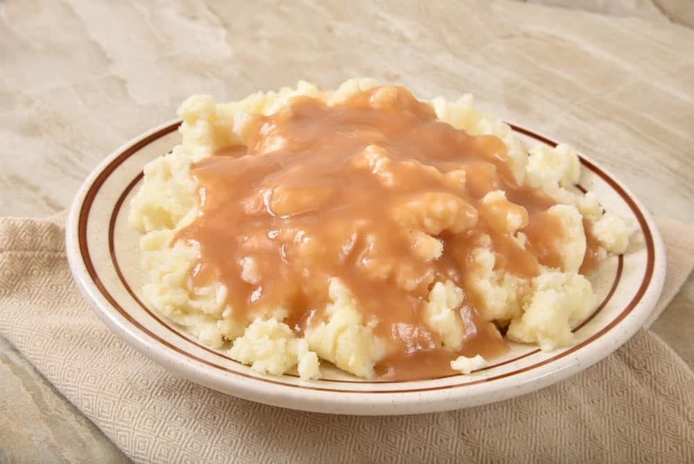 A serving bowl of mashed potatoes and turkey gravy