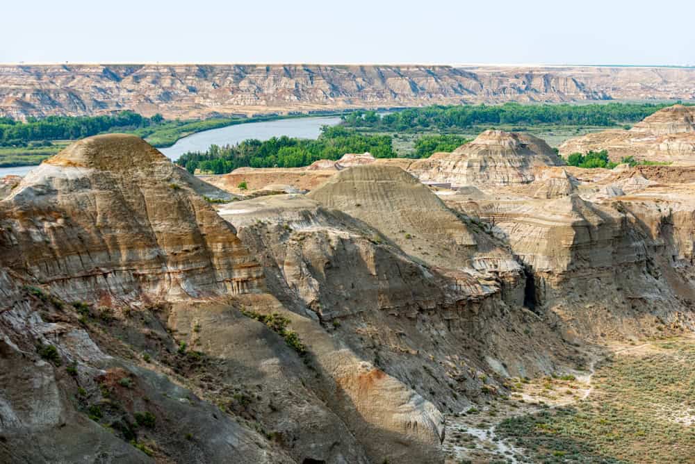 Dinosaur Provincial Park panorama: Vast badlands, rich with fossils, under endless skies. Mesmerizing hoodoos, dinosaurs' ancient home. Nature's masterpiece!
