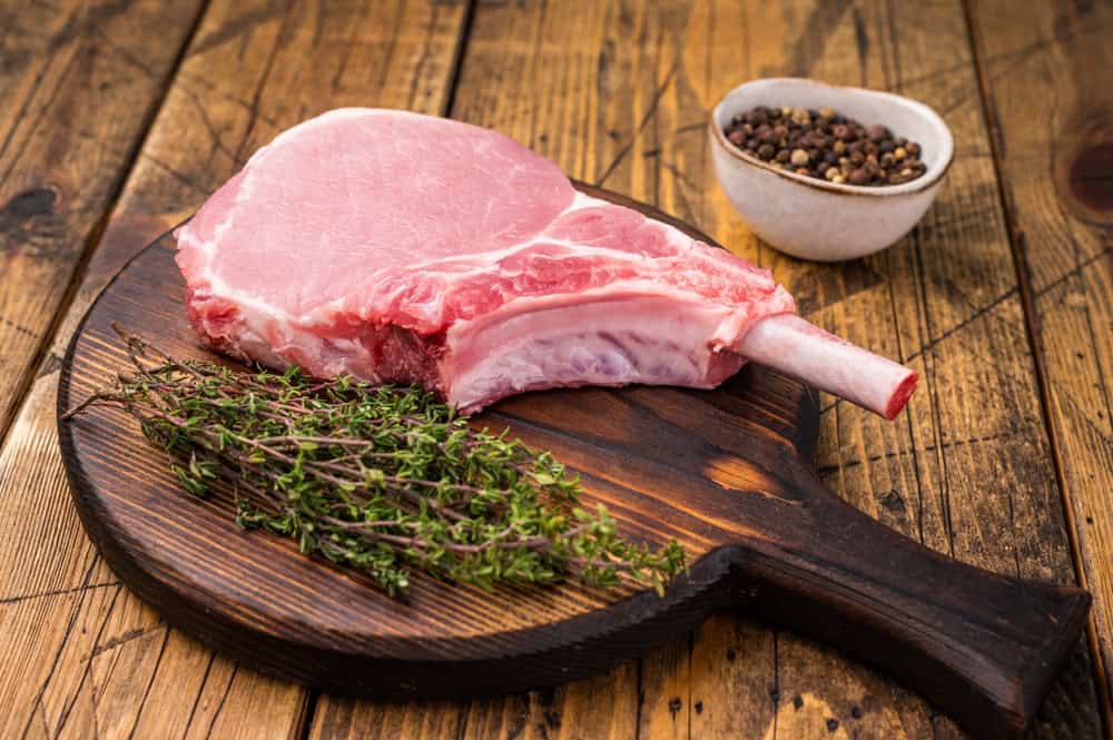 Pristine pork loin chop, featuring a thick cut and beautiful marbling, ideal for a hearty dinner. wooden background. top view.